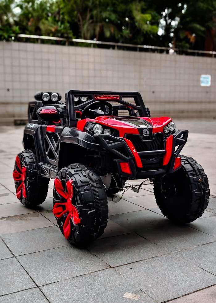 Vibrant red and black toy car photographed outdoors in an urban setting.